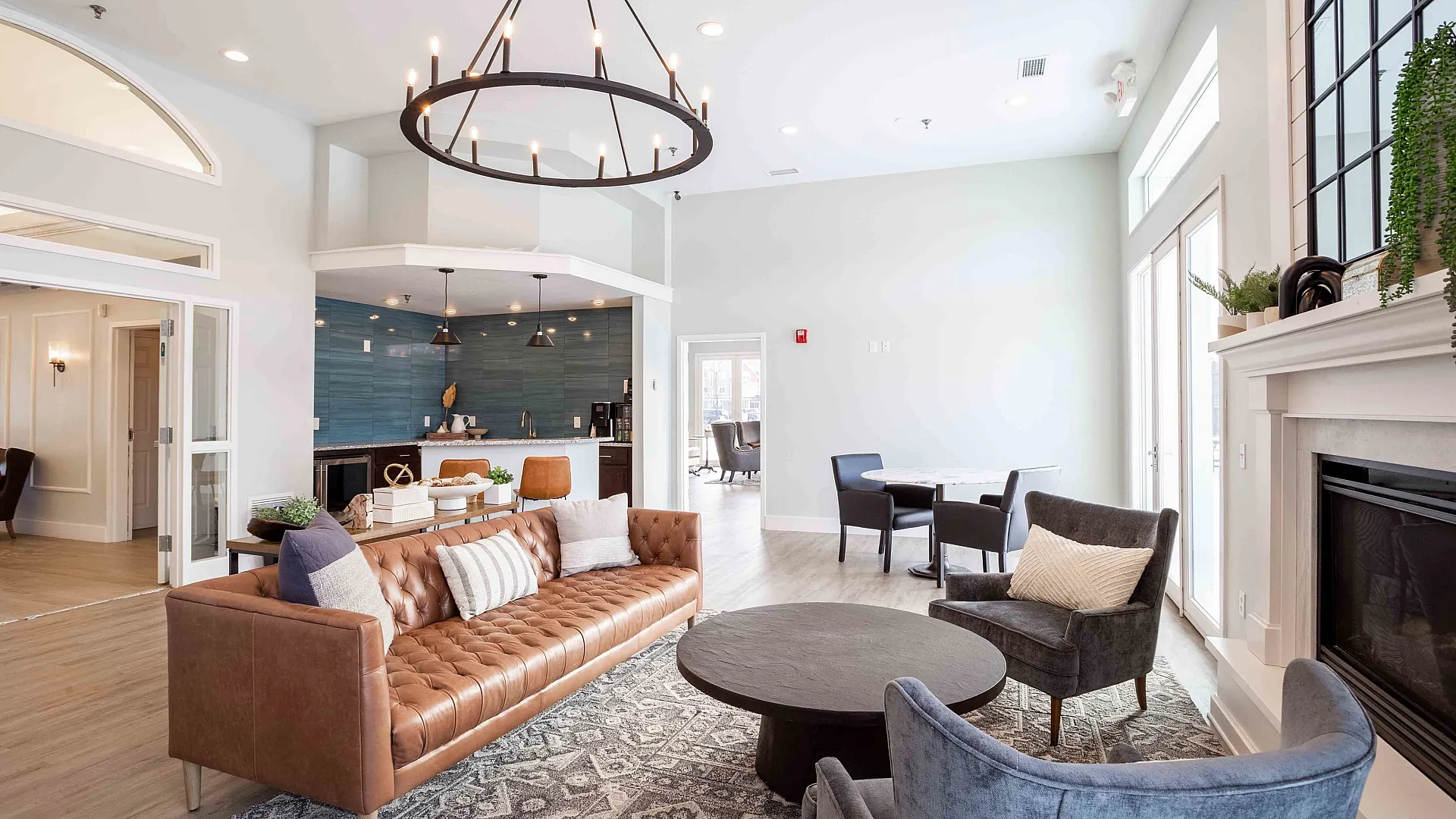 Chic contemporary living room boasting a plush leather sofa, elegant chandelier, and stylish open kitchen with modern island seating.