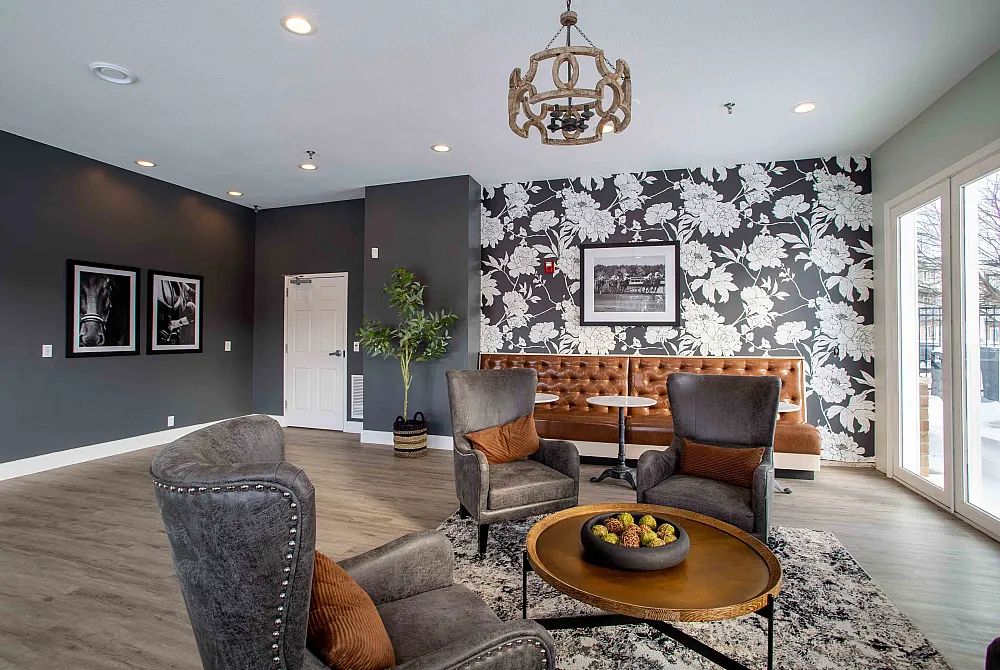 Elegant lounge area featuring stylish armchairs, a floral accent wall, and a shiny wooden centerpiece table exuding modern sophistication.