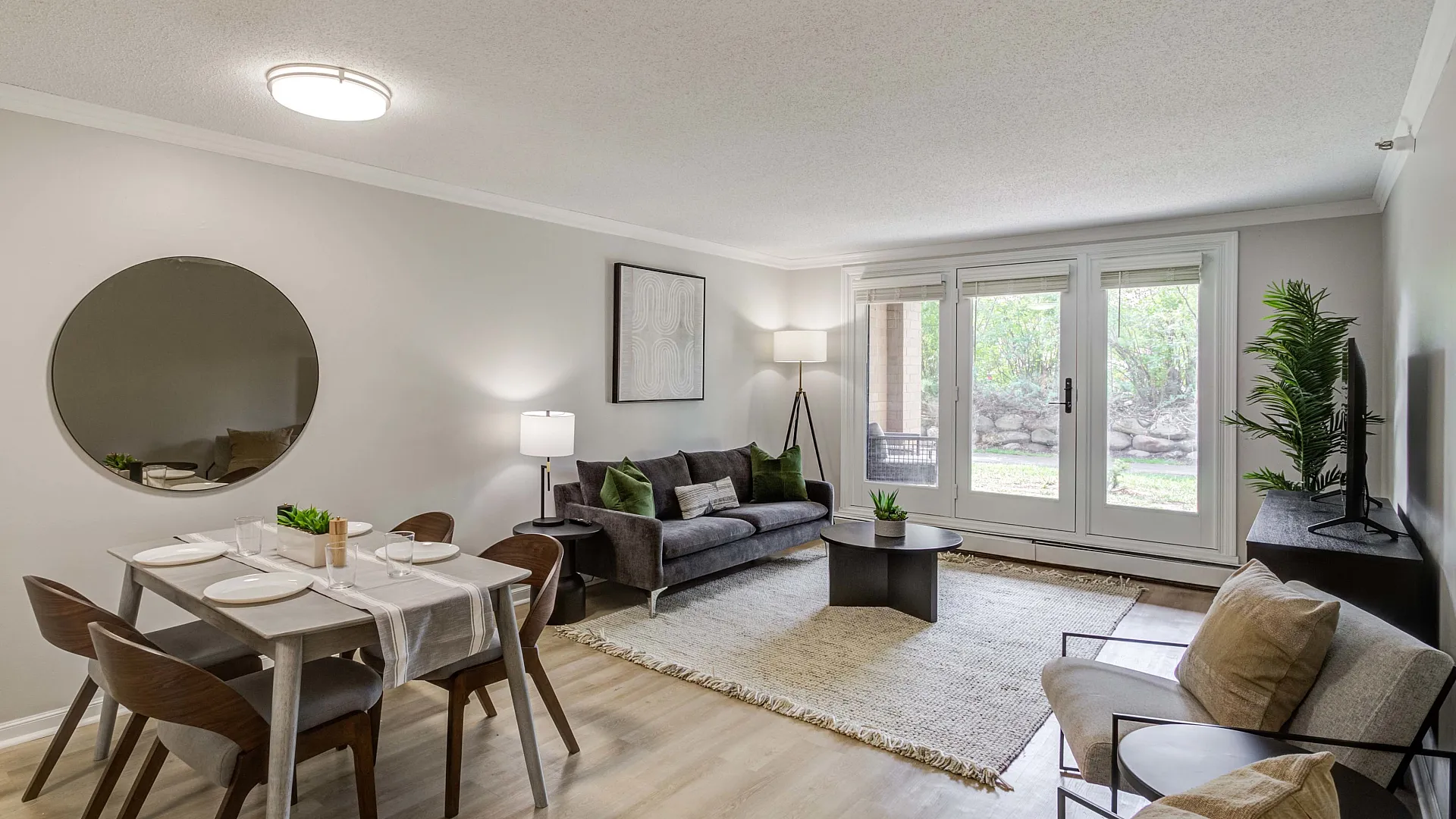 Elegant open living and dining area with stylish furniture, large windows inviting natural light, and a chic modern aesthetic.