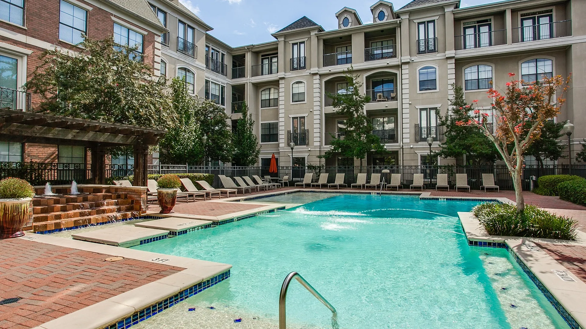 Luxurious apartment complex with a stunning outdoor pool, elegant architecture, and comfortable lounge chairs in a relaxing atmosphere.