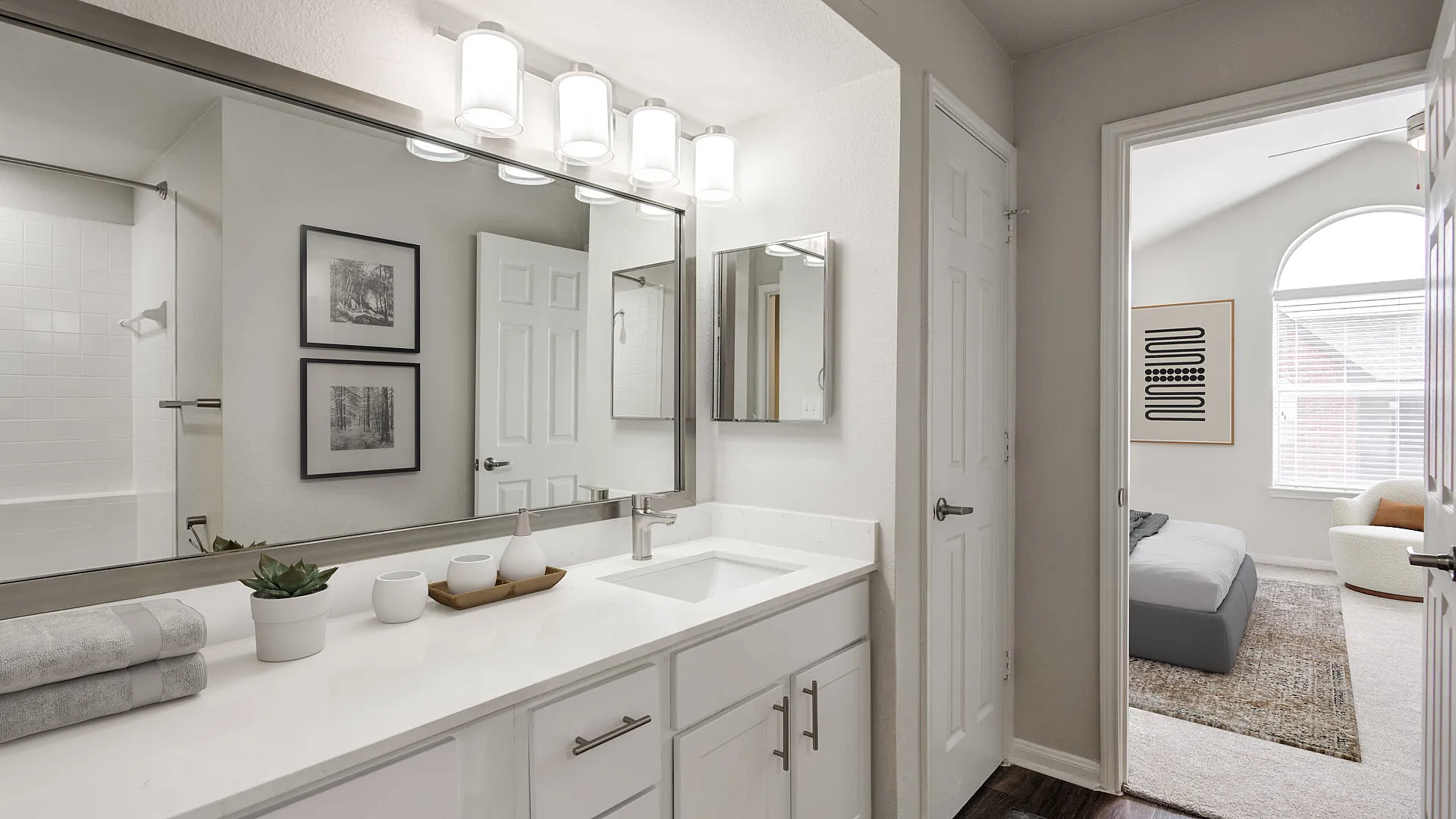 Elegant bathroom with modern vanity, large mirror, and stylish lighting, leading into a cozy bedroom with natural light.