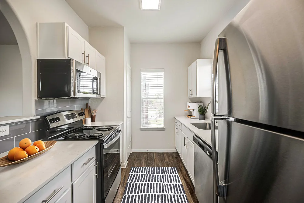 Modern kitchen featuring sleek stainless steel appliances, bright cabinetry, and stylish countertops with a cozy window view.