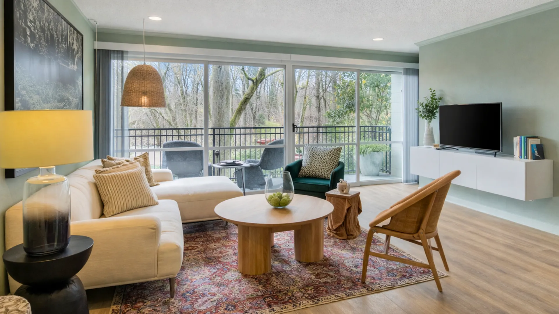 Inviting living room with modern decor, featuring a cozy white sofa, chic accent chair, and large windows offering a serene view of lush greenery.