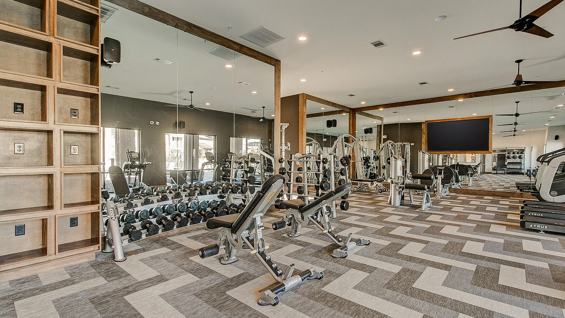 Luxurious apartment gym with modern equipment, mirrored walls, and stylish flooring, perfect for a comprehensive workout experience.