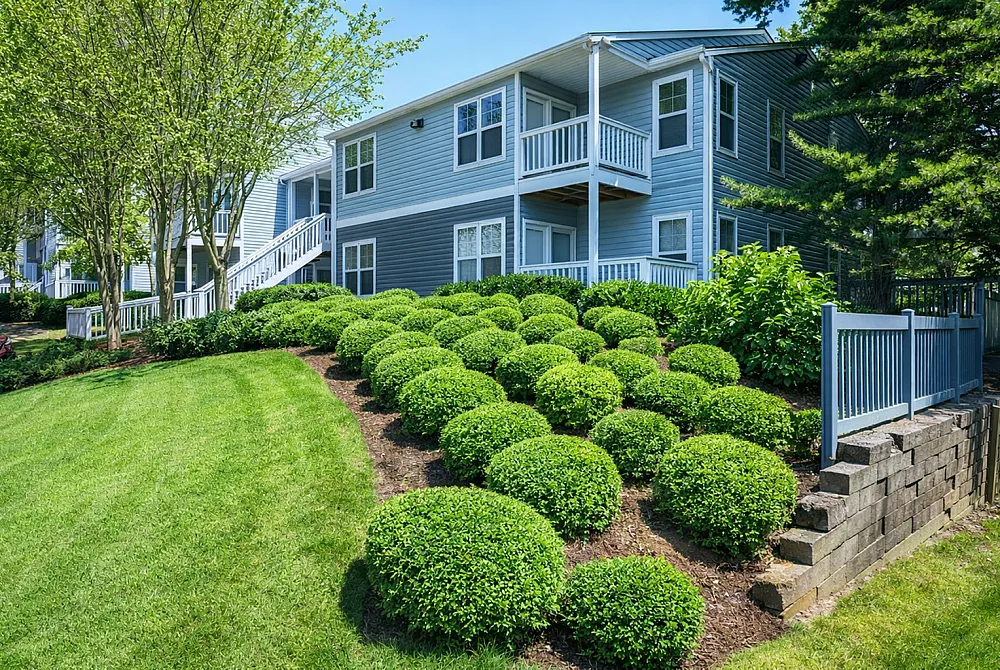 Charming blue apartment building with lush landscaped gardens and vibrant green lawn, offering a serene and welcoming ambiance.