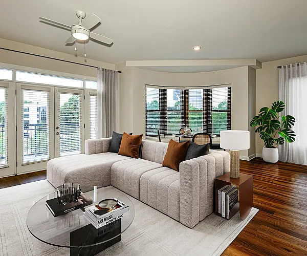 Chic and inviting living room with a plush sectional sofa, elegant decor, and expansive windows offering scenic views. Features hardwood flooring, contemporary furniture, and abundant natural light.