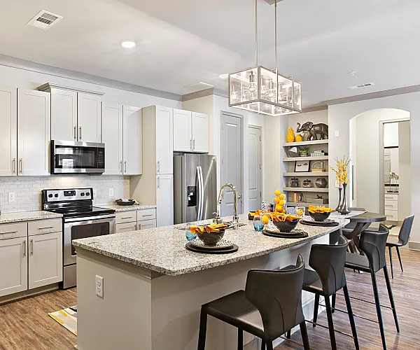 Modern kitchen with granite countertops and sleek cabinetry, featuring a stylish breakfast bar and elegant pendant lighting.