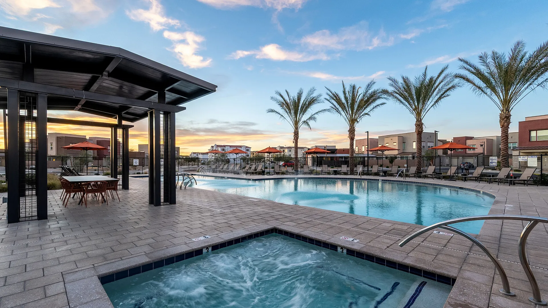 Luxurious resort-style swimming pool and spa area with palm trees and sunset skies, perfect for relaxation and leisure.