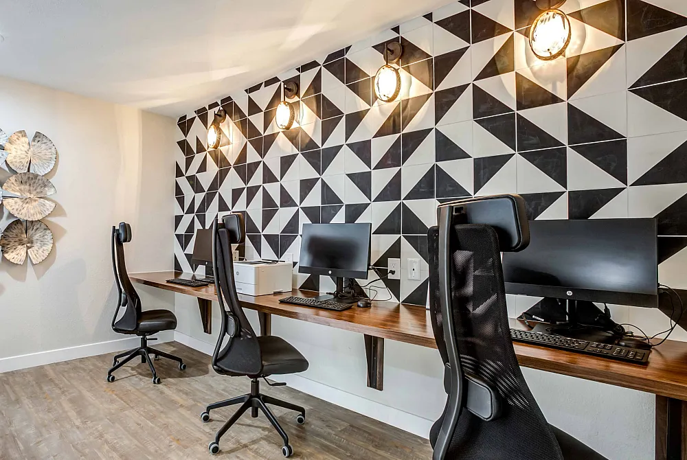 Contemporary workspace featuring ergonomic chairs, sleek wooden desks, and stylish geometric wall design.