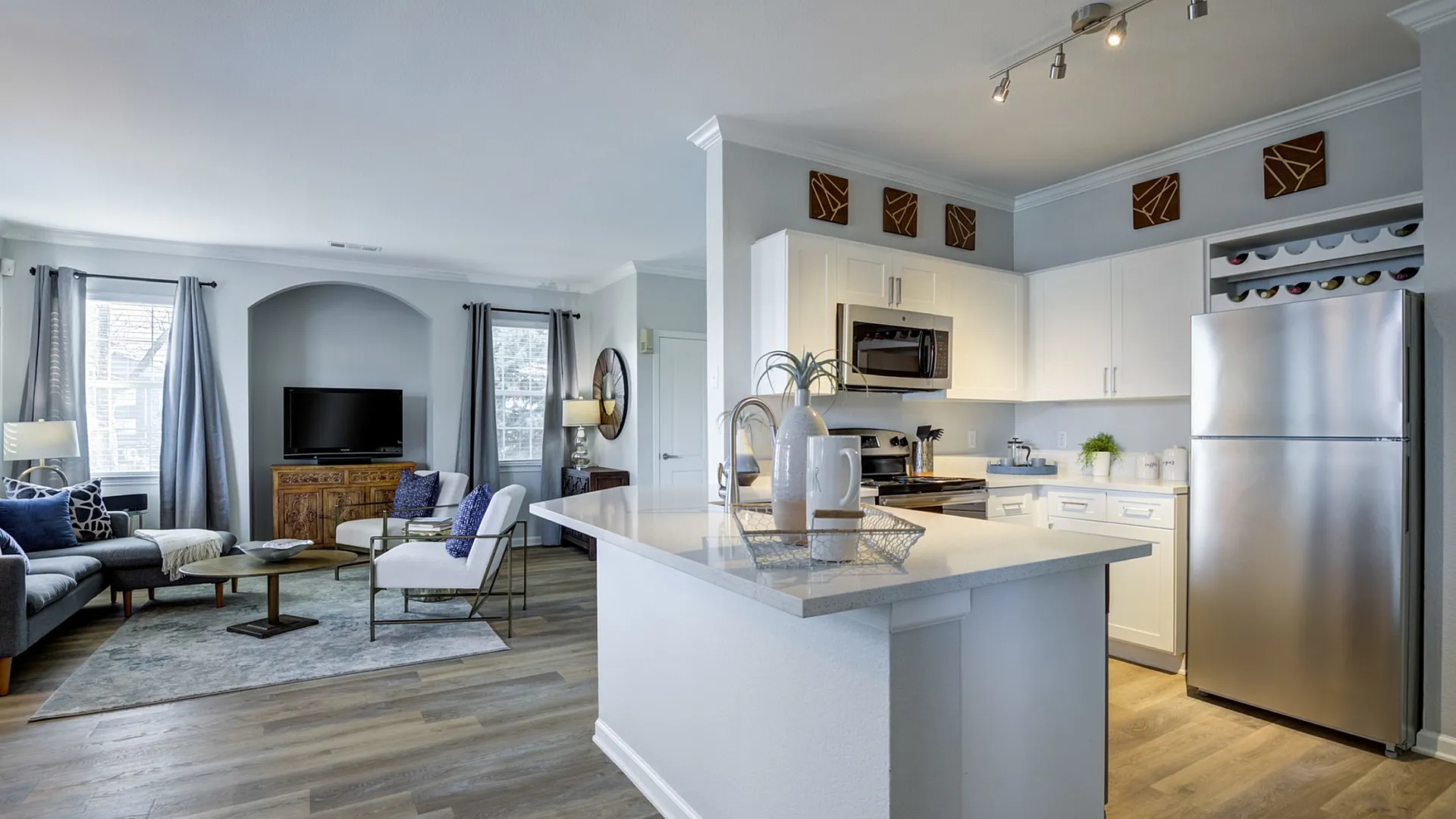 Modern open-plan living room and kitchen with sleek hardwood floors, stylish decor, and abundant natural light.