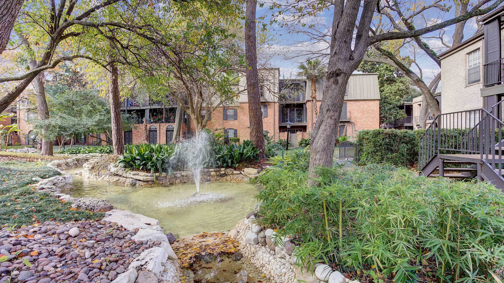 Charming three-story apartment building with elegant balconies, surrounded by lush landscaping and vibrant flowers, located at Creole on Yorktown.