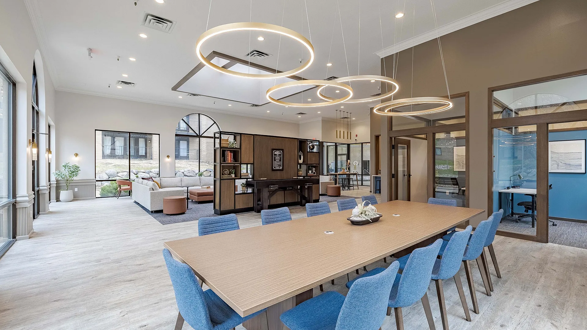 Elegant community lounge area featuring modern blue seating, vibrant artwork, and a spacious open layout with views of the indoor pool.