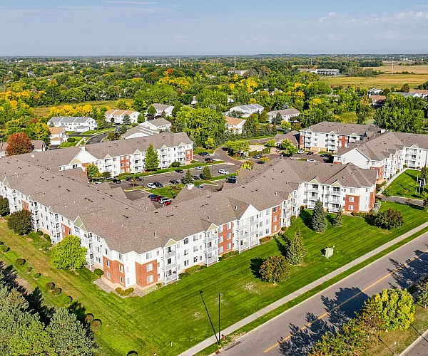 Expansive aerial view of a charming apartment complex surrounded by lush greenery and vibrant trees, showcasing serene suburban living.