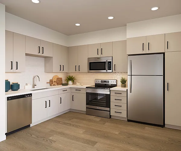 Modern kitchen with sleek stainless steel appliances, elegant beige cabinetry, and warm wood flooring.