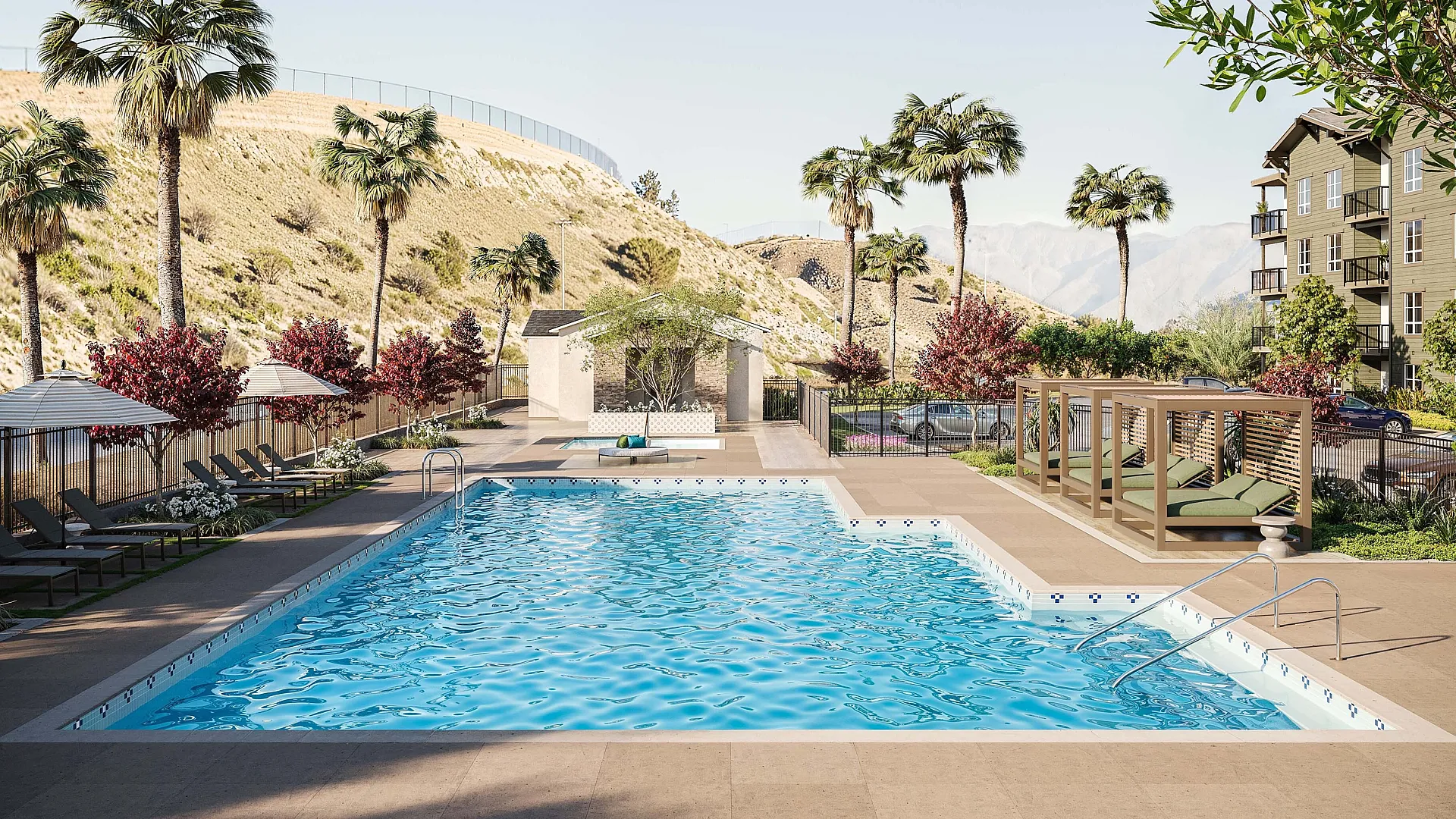Inviting outdoor pool area with sun loungers, umbrellas, and lush palm trees against a scenic hill backdrop, creating a perfect relaxation spot.