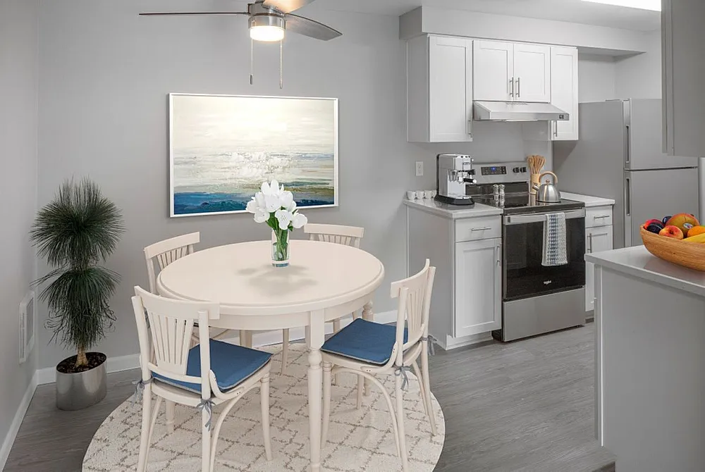Charming modern kitchen and dining area featuring sleek white cabinetry, stylish round table with chairs, and bright, inviting decor.