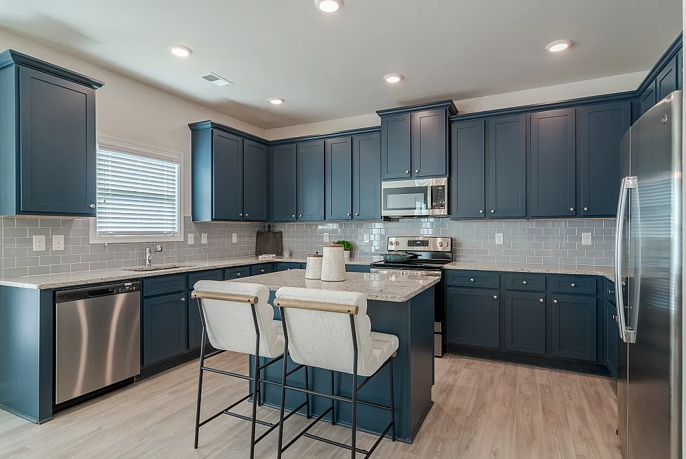 Modern kitchen with sleek blue cabinetry, stainless steel appliances, and a spacious island with stylish bar seating.
