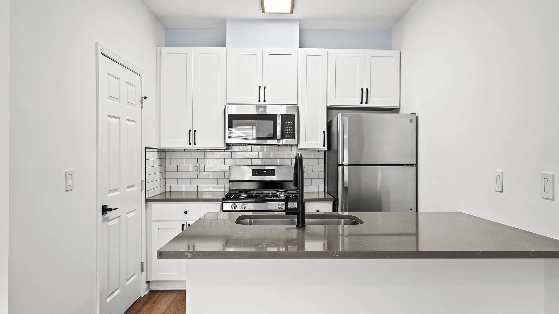 Modern kitchen with sleek stainless steel appliances, elegant white cabinetry, and a stylish subway tile backsplash.