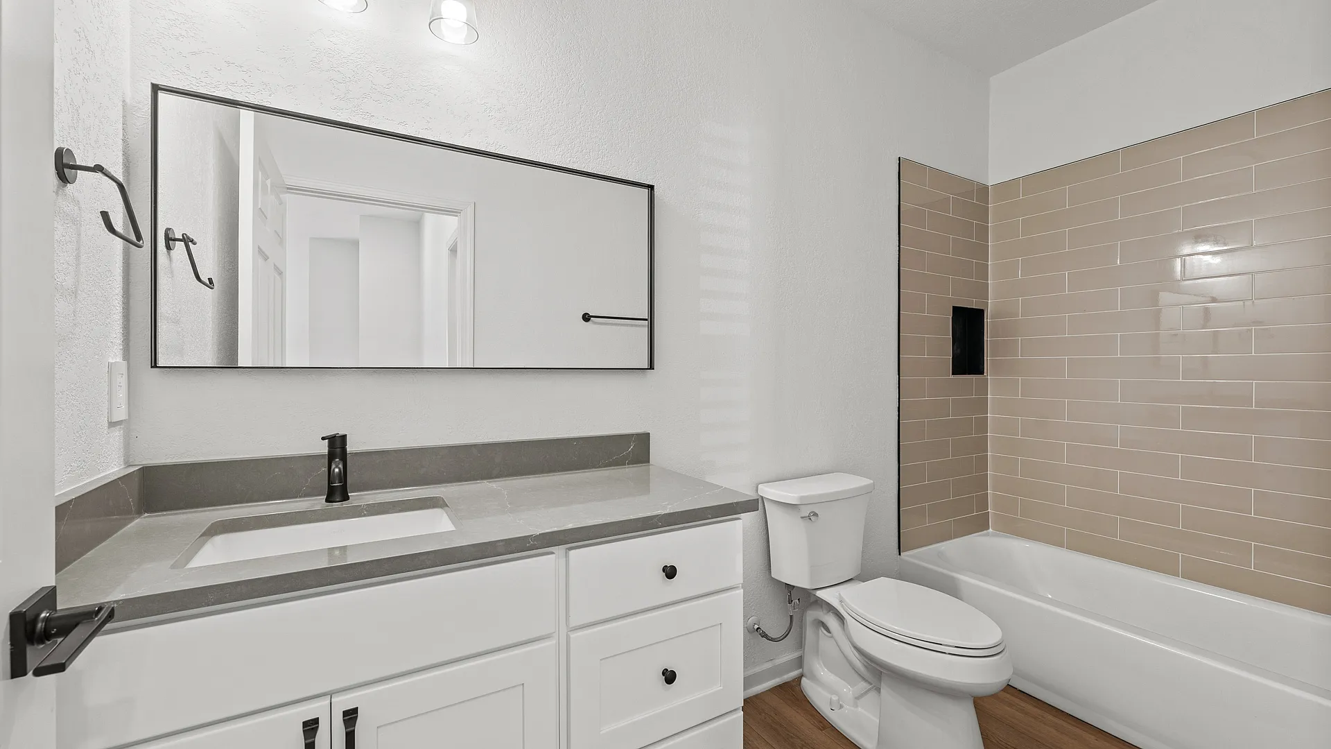 Modern bathroom with sleek fixtures, elegant light gray countertop, and stylish beige tile wall accentuating the bathtub area.