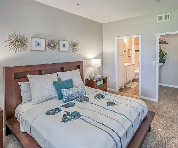 Elegant bedroom with a plush bed, decorative wall art, and an ensuite bathroom featuring modern design. Spacious walk-in closet with greenery adds a touch of nature.