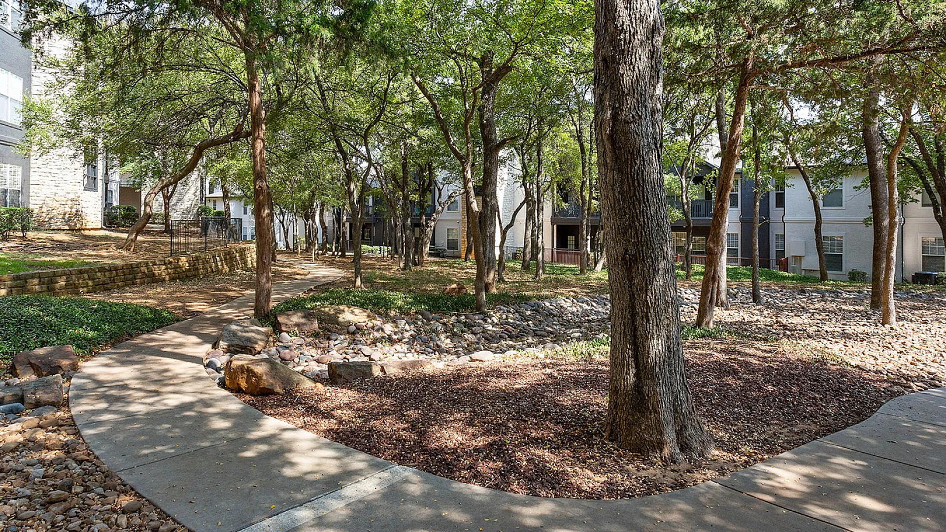 Tranquil apartment community surrounded by lush trees and serene pathways.