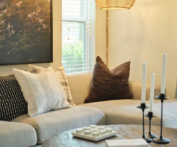 Cozy living room with a stylish gray sectional couch, accent pillows, a rustic wooden coffee table, and soft ambient lighting.