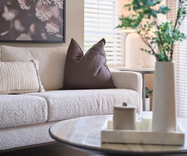 Cozy living room featuring a plush cream sofa with stylish cushions, a marble coffee table, and elegant decor accents.