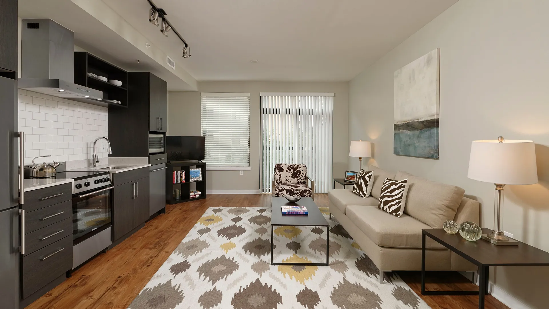 Modern open-concept living area with sleek kitchen, cozy seating, and stylish decor, featuring hardwood floors and abundant natural light.