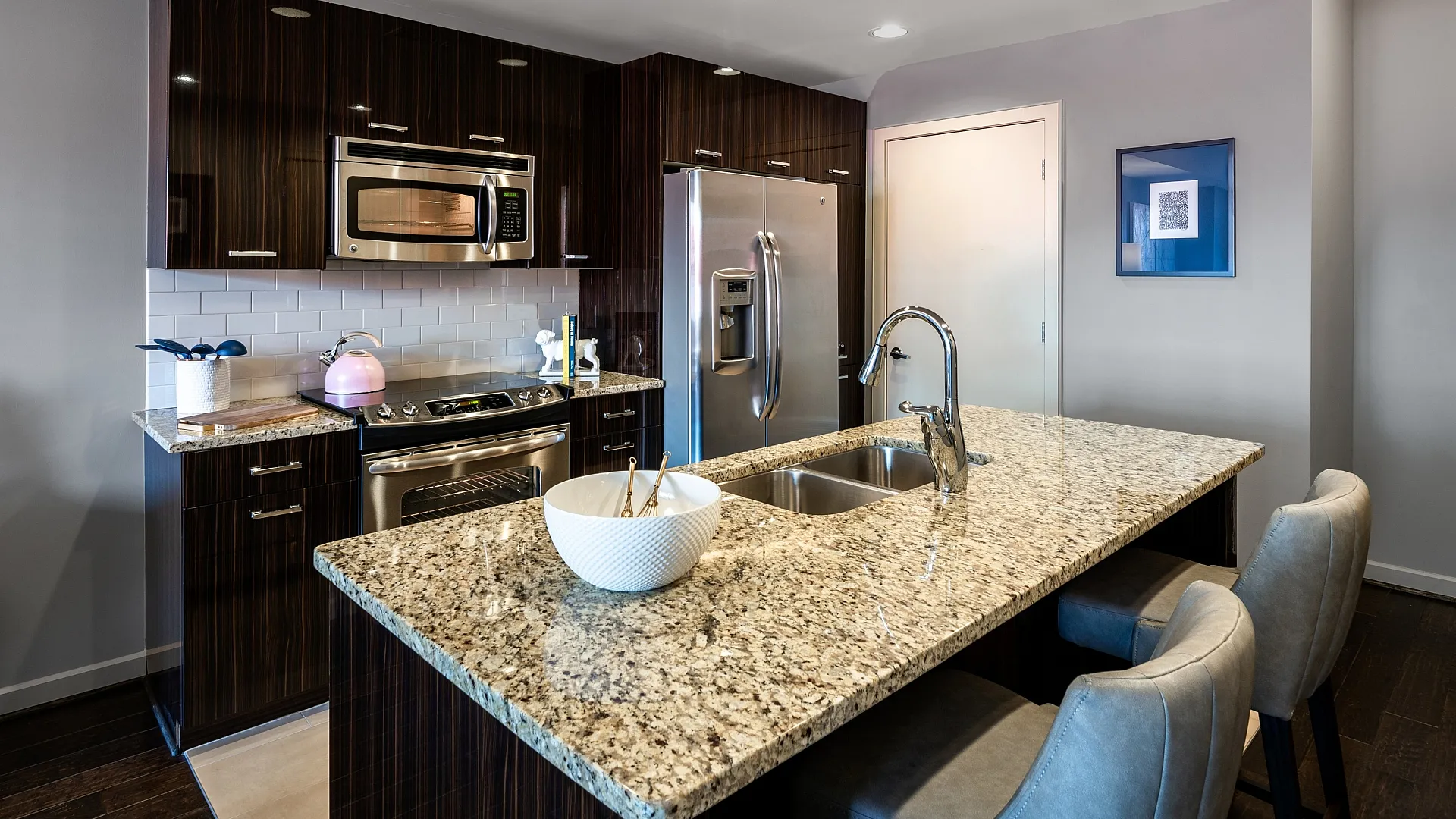 Modern kitchen with granite countertops, stylish dark wood cabinets, stainless steel appliances, and elegant seating for a contemporary lifestyle.