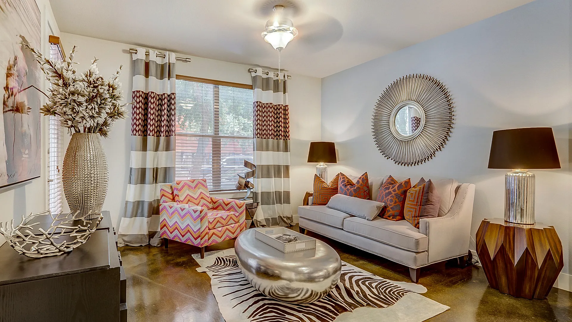 Chic and modern living room featuring stylish decor, a comfortable couch with colorful cushions, and a unique metallic coffee table on a zebra-patterned rug.