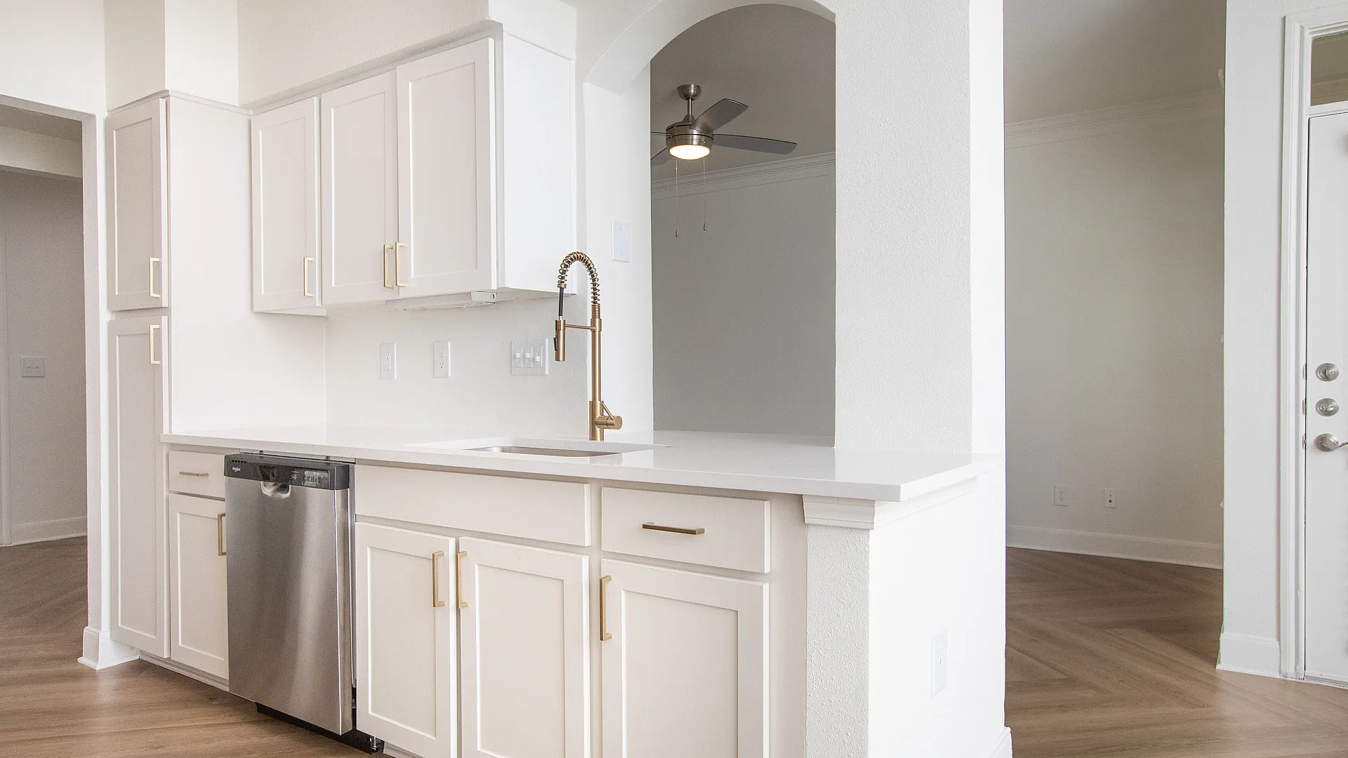 Updated kitchen with gold finishes looking into living room