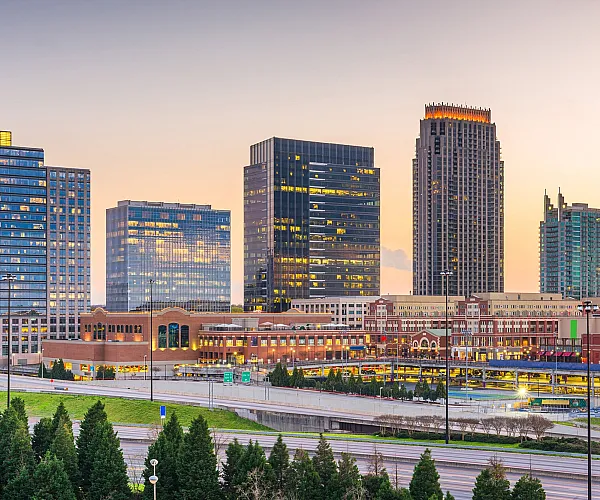 Vibrant city skyline at sunset featuring modern high-rise buildings and bustling urban streets.