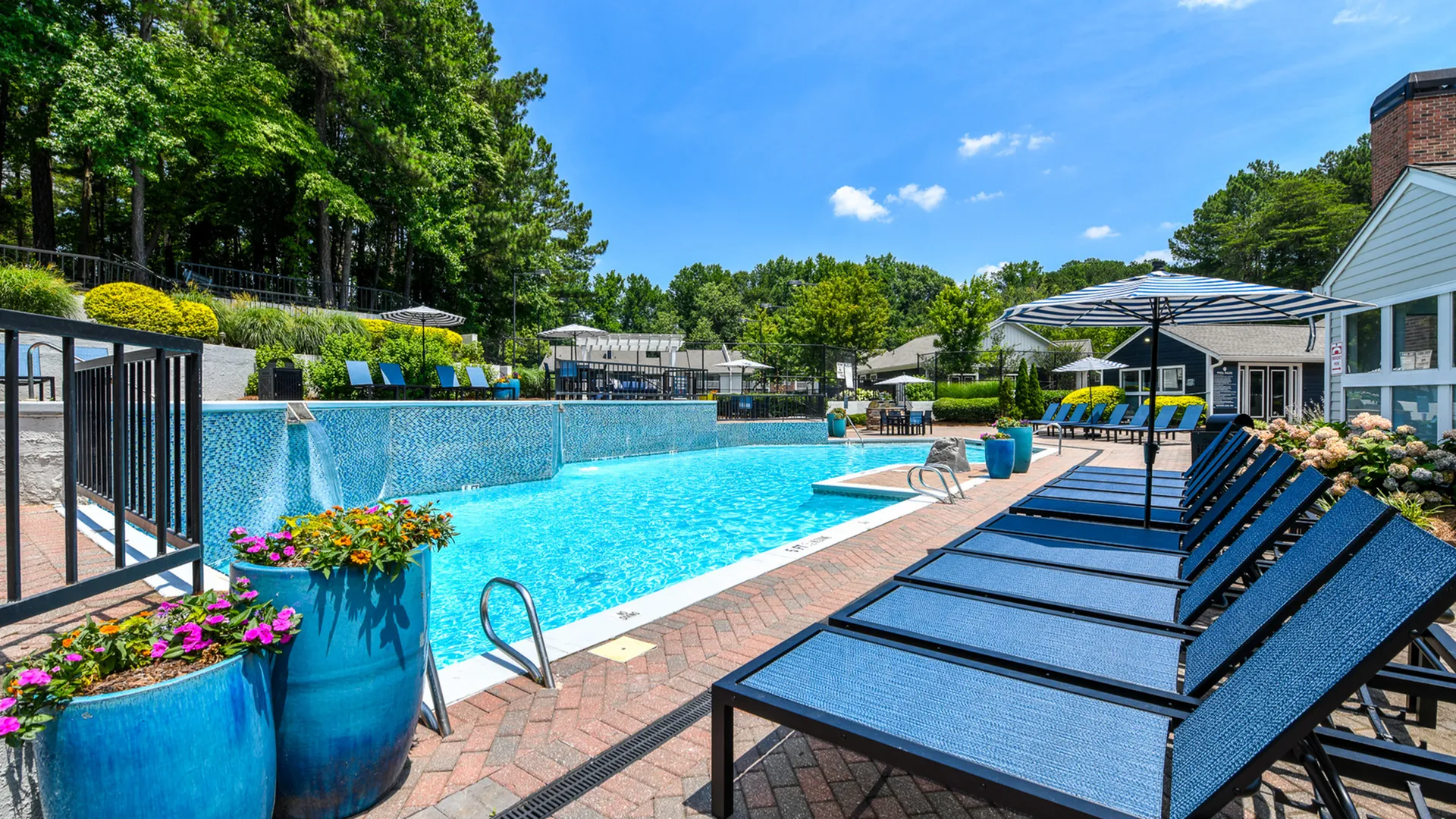 Luxurious outdoor pool area with comfortable loungers, vibrant floral arrangements, and lush green surroundings, perfect for relaxation.