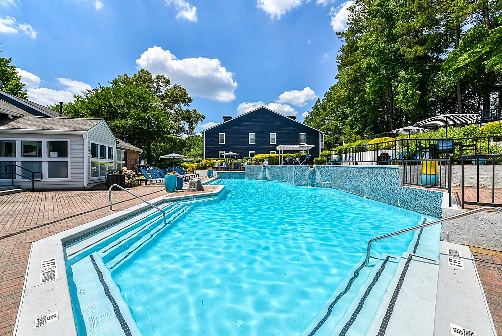 Inviting outdoor pool area with crystal-clear water, surrounded by lush greenery and modern poolside seating, perfect for relaxation and enjoyment.