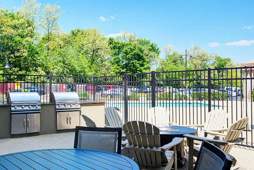 Inviting outdoor patio area featuring a sleek barbecue setup and cozy seating with views of lush greenery.