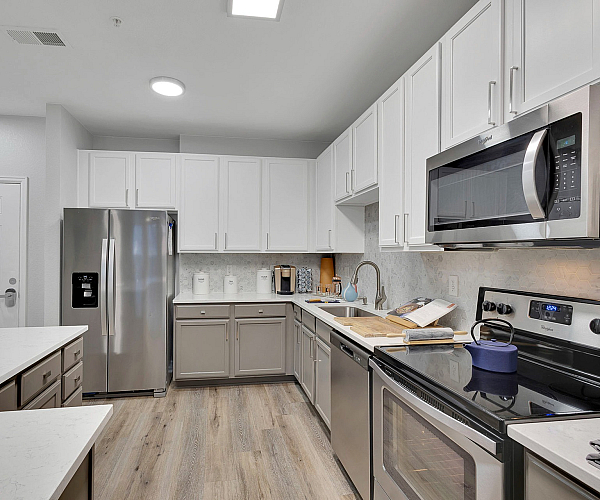 Modern kitchen with sleek stainless steel appliances, elegant white cabinets, and spacious countertops offering a luxurious cooking experience.