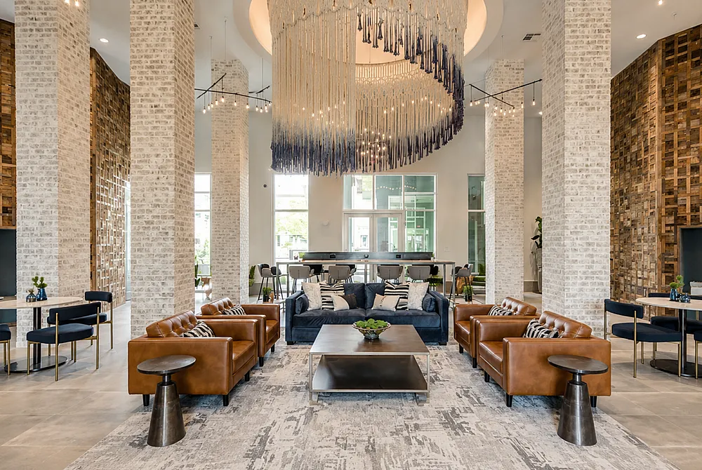 Luxurious apartment lounge featuring elegant leather sofas, a stunning modern chandelier, and chic decor. Stylish open space with high ceilings and exquisite detailing.