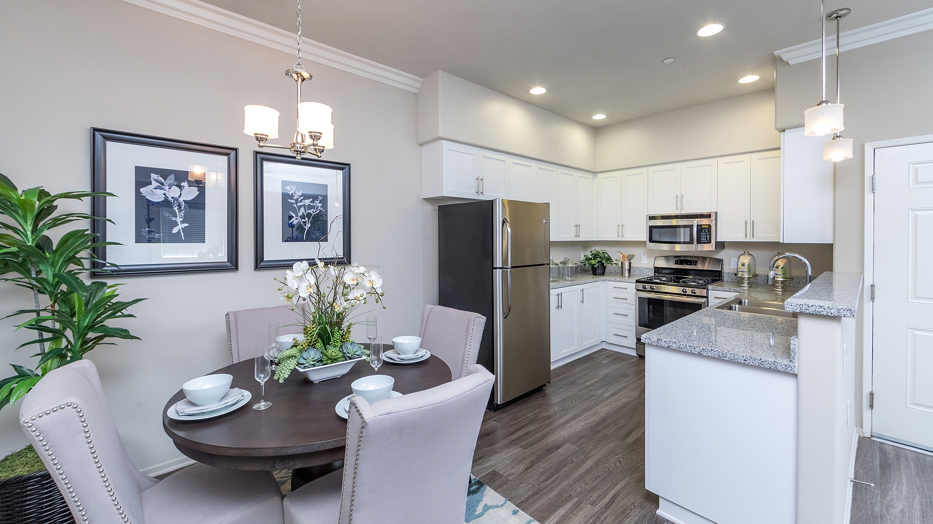 Modern open-concept kitchen and dining area with elegant lighting, sleek stainless steel appliances, and stylish decor.