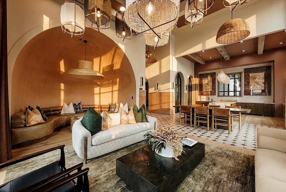 Elegant living space with stylish decor, featuring a cozy curved sofa, abundant natural light, and chic pendant lighting.