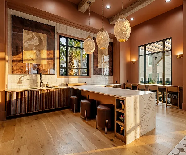 Luxurious kitchen with modern decor, featuring elegant pendant lights, wooden accents, and a spacious marble island overlooking a sunlit window view.
