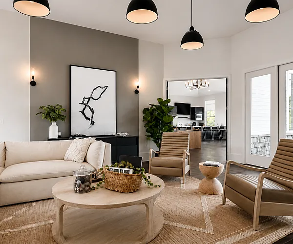 Elegant living room with modern decor featuring a cozy sectional sofa, stylish armchairs, and a chic coffee table, enhanced by natural light streaming through glass doors.