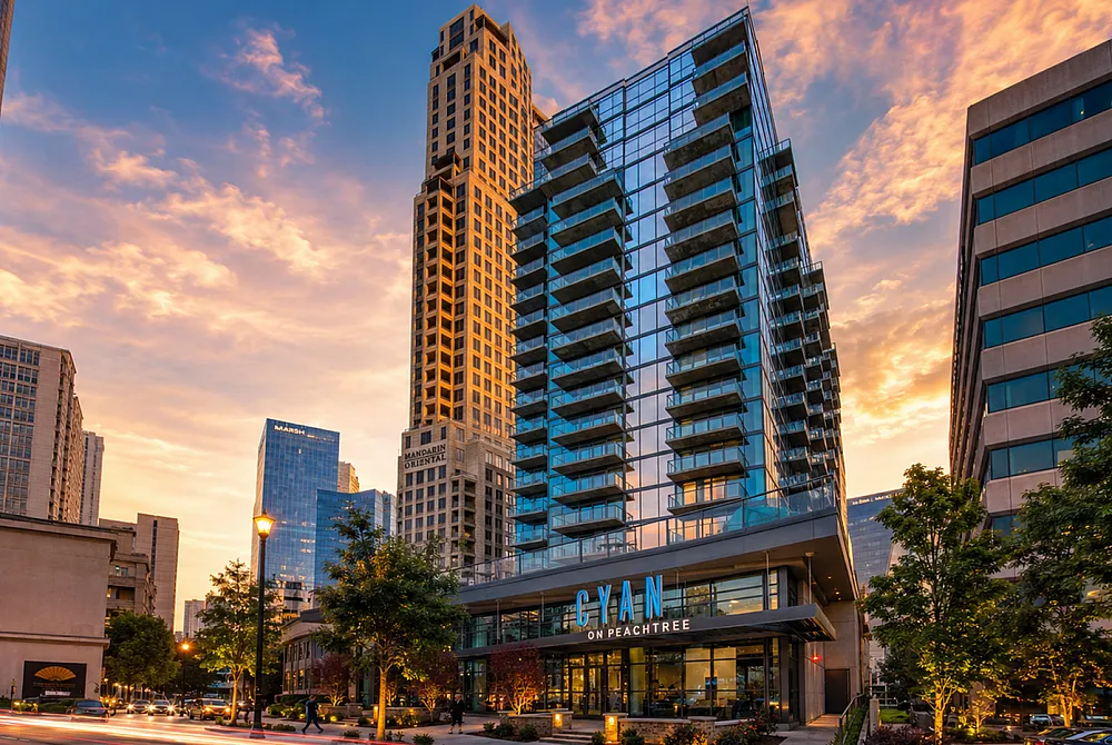 Stunning urban skyline at dusk featuring the Cyan on Peachtree with sleek glass architecture, surrounded by vibrant city lights and a colorful sunset sky.