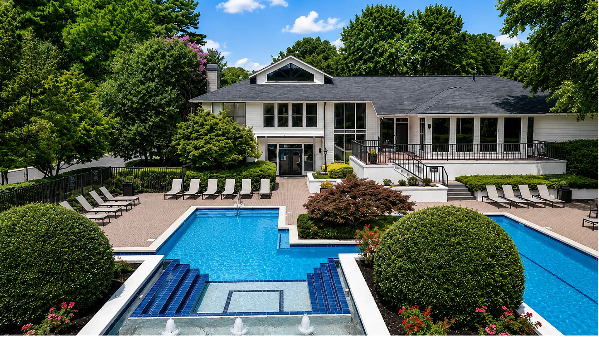 Luxurious residential clubhouse surrounded by lush greenery, featuring a sparkling swimming pool and elegant outdoor lounging area.