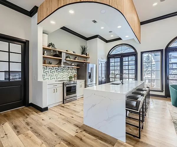 Luxurious modern kitchen with stylish island, sleek countertops, and floor-to-ceiling windows offering a bright, inviting ambiance.