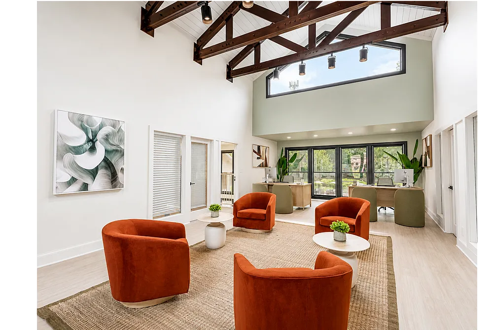 Bright and airy modern living space with elegant orange chairs, expansive windows, and stylish wooden beams, offering a perfect blend of comfort and sophistication.