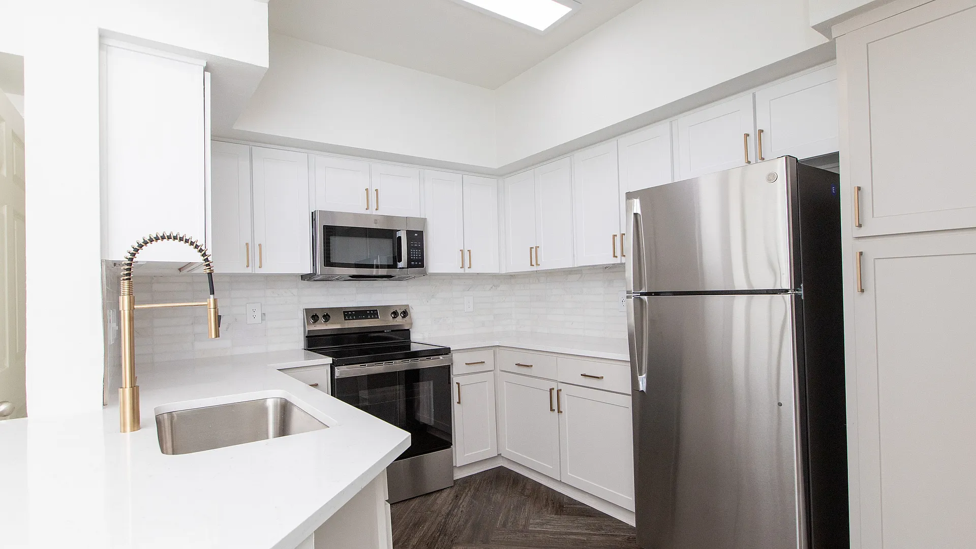 Modern kitchen with sleek stainless steel appliances, elegant white cabinetry, and a stylish waterfall faucet.