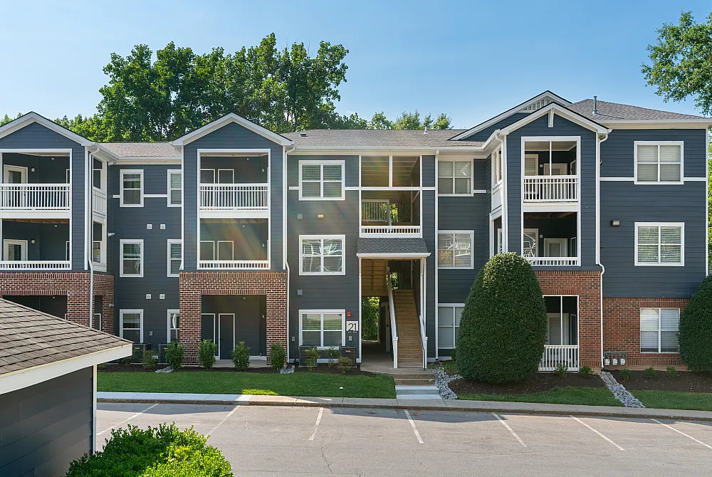 Attractive modern apartment complex with three levels, spacious balconies, and lush greenery, offering a welcoming and serene living environment.