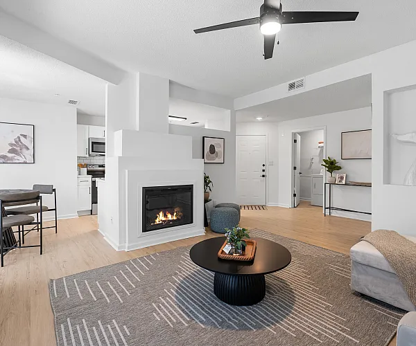 Modern living space with sleek fireplace, cozy sectional, and elegant dining area leading to a stylish kitchen.