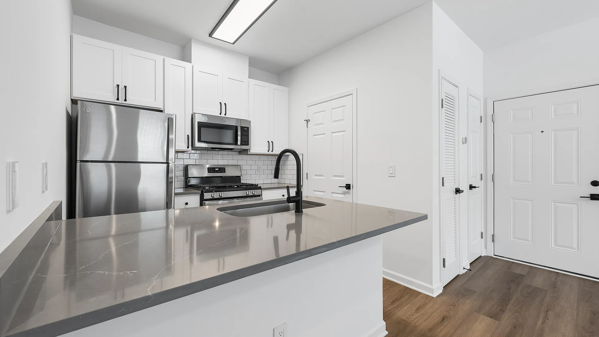 Sleek modern kitchen with stainless steel appliances, elegant cabinetry, and a polished stone countertop.