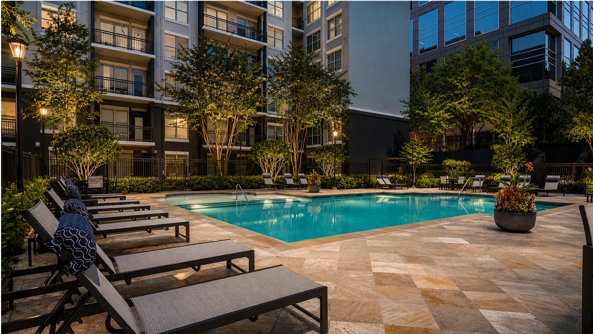 Elegant poolside oasis with modern lounge chairs and lush greenery in a sophisticated apartment complex.